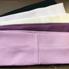 A stack of five elastic hairbands in various colors including black, white, beige, purple, and pink.