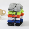 A stack of twelve breathable men's athletic socks in various colors including gray, lime green, orange, white, and blue.