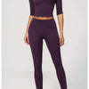 A woman models a purple women's yoga and fitness leggings set in a full-length shot.