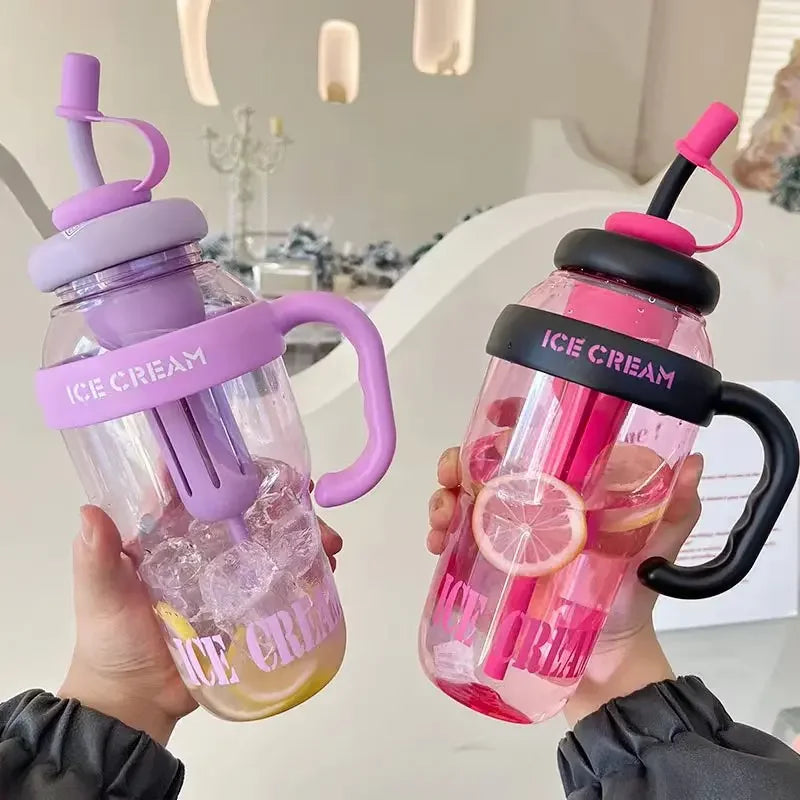 A hand holds a large capacity portable plastic drinking cup filled with pink liquid and ice cubes.