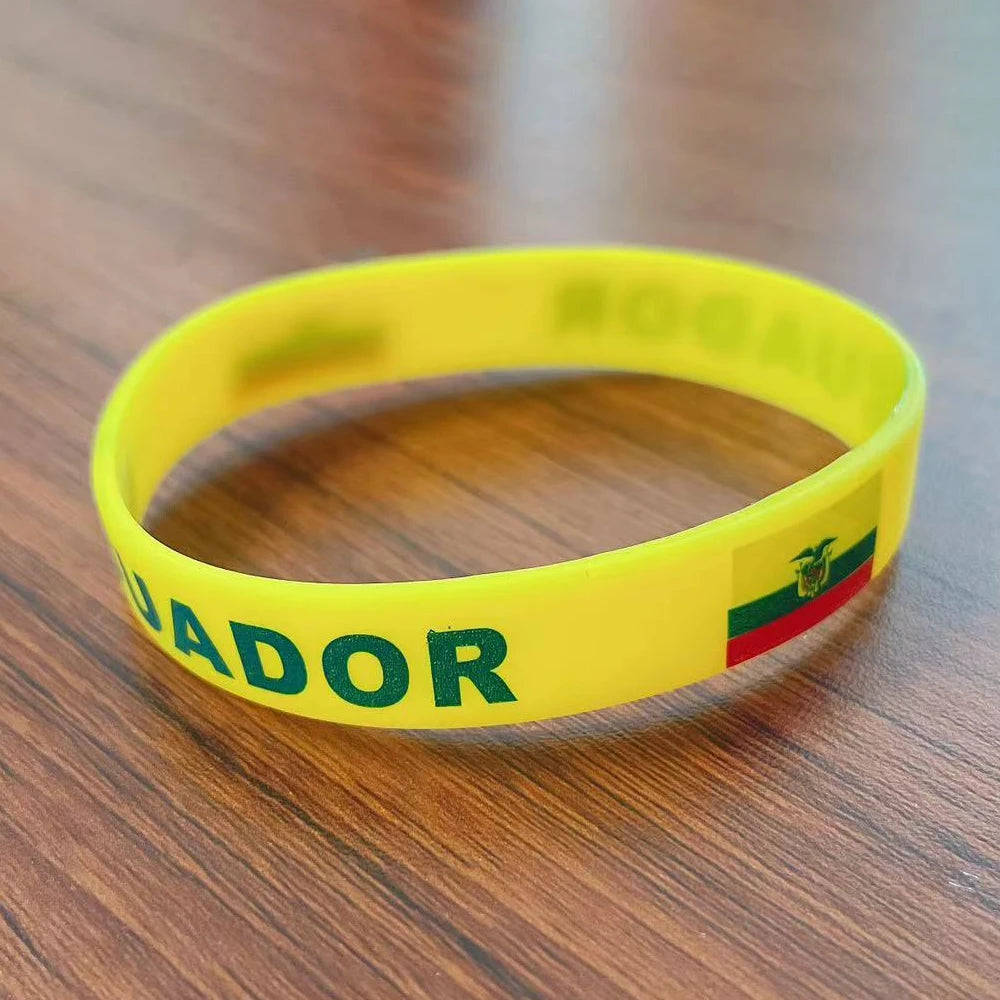 Yellow silicone wristband with the word 'JADOR' printed on it, resting on a wooden surface.