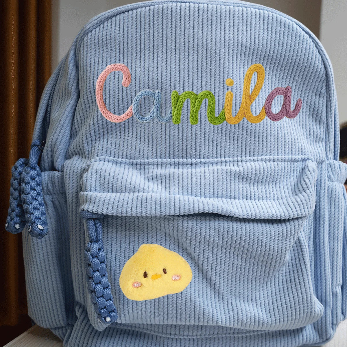 Hellblaue Cordhosen-Rucksack mit gesticktem Namen Camila und einem gelben Küken