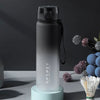 Eine hohe, matte graue isolierte Wasserflasche mit schwarzem Verschluss und Riemen wird auf einem hellblauen Ständer präsenti