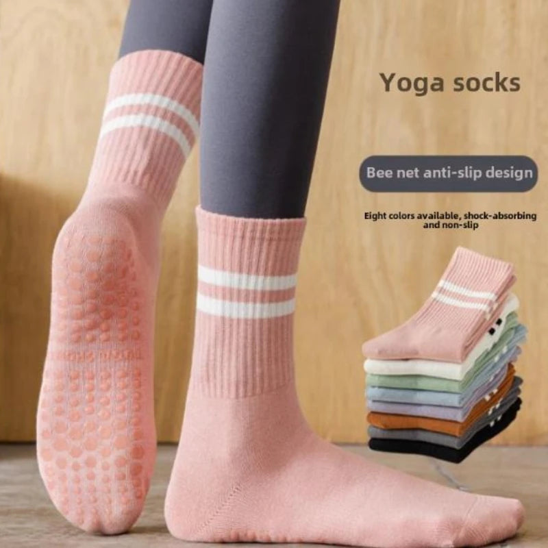 A pair of peach colored yoga socks with white stripes shown on a person's foot.