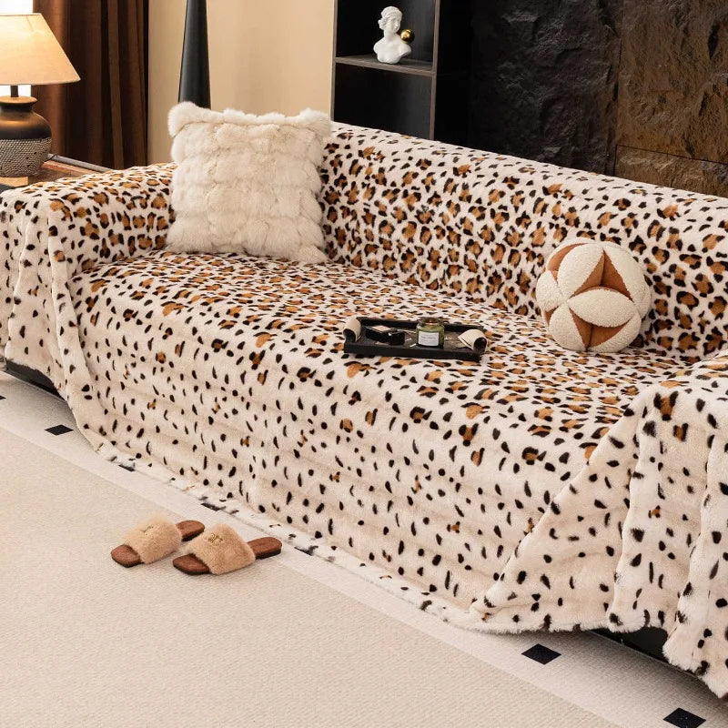 A plush leopard print sofa cover blanket draped over a sofa, featuring a white fluffy pillow and decorative accents.