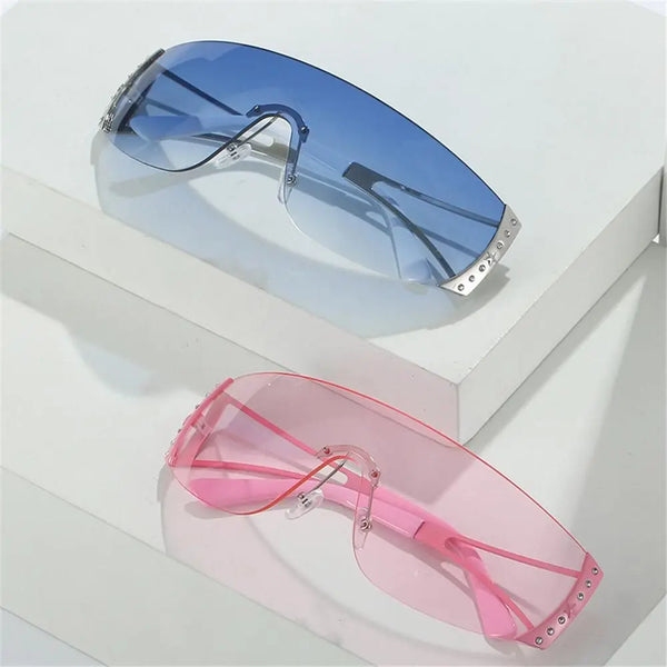 Pair of Y2K futuristic gradient sunglasses with a blue lens resting on a white surface.