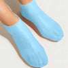 Light blue silicone moisturizing socks worn on a foot.