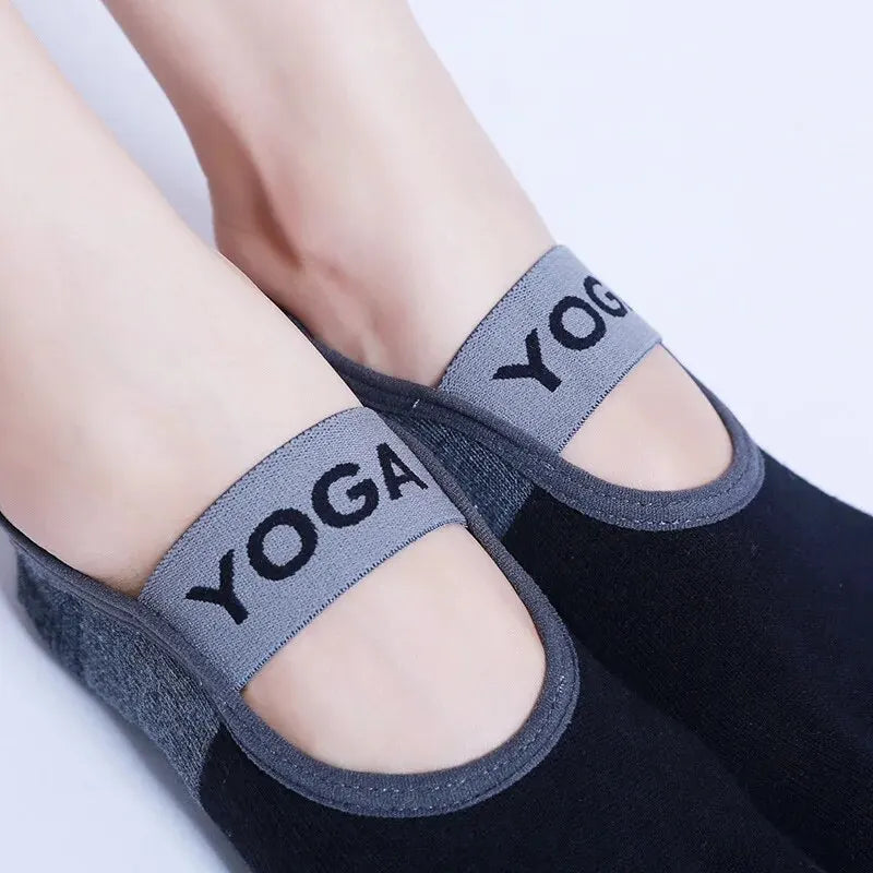 Gray silicone yoga socks worn on feet against a dark background.