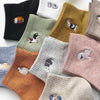 A collection of embroidered cotton socks in various muted colors including black, olive green, beige, and pink.
