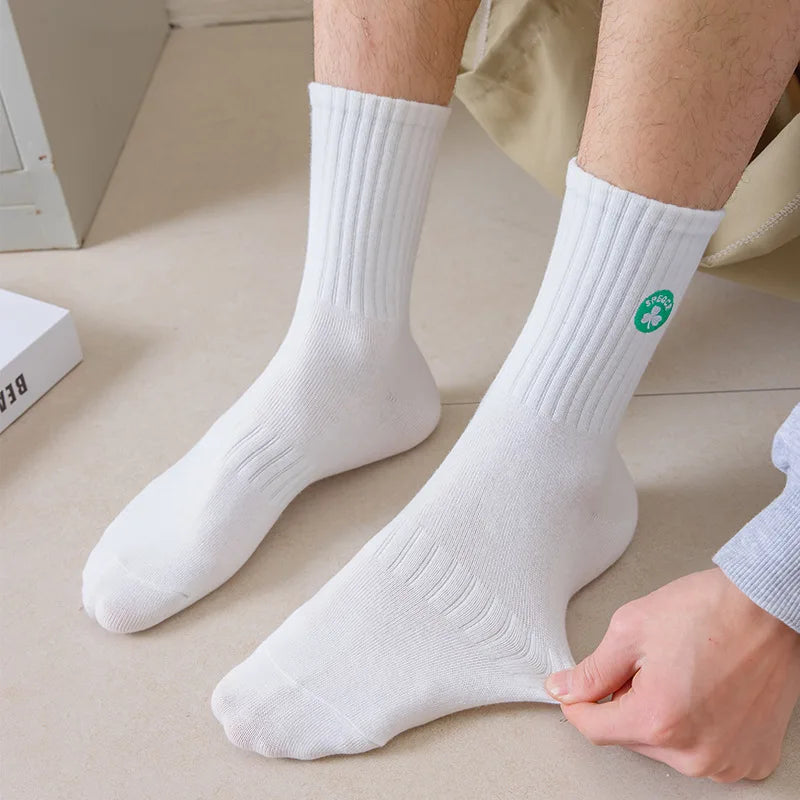 A pair of white men's athletic crew socks are shown on a person's leg.