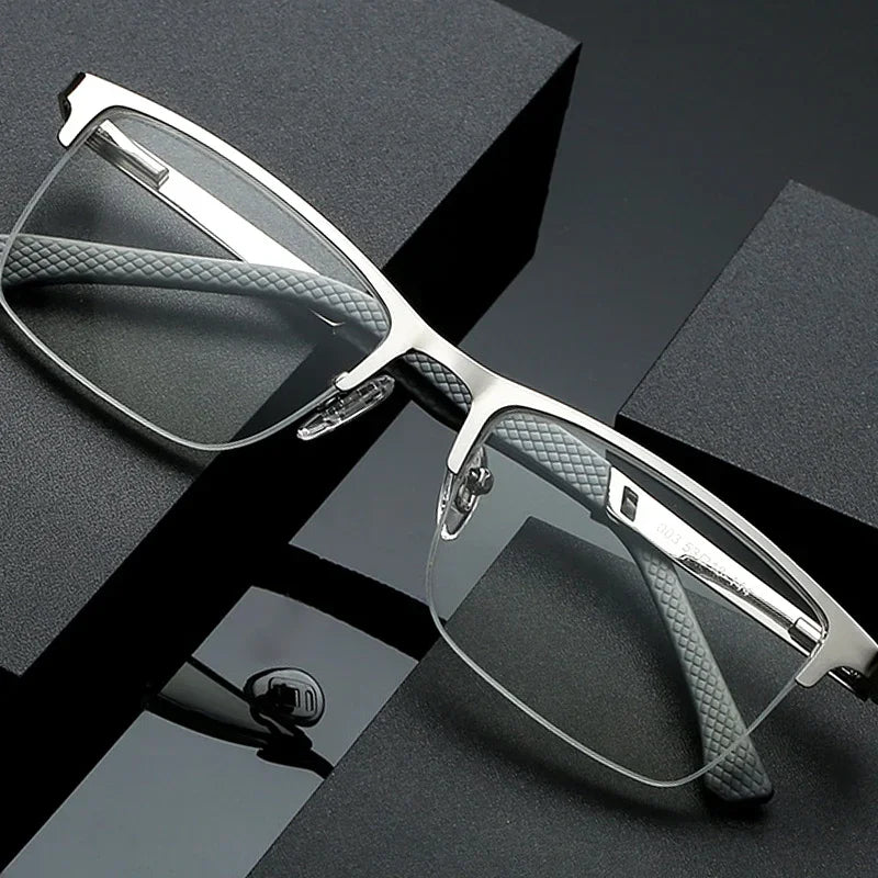 A pair of silver-framed reading glasses with clear lenses resting on a dark surface.