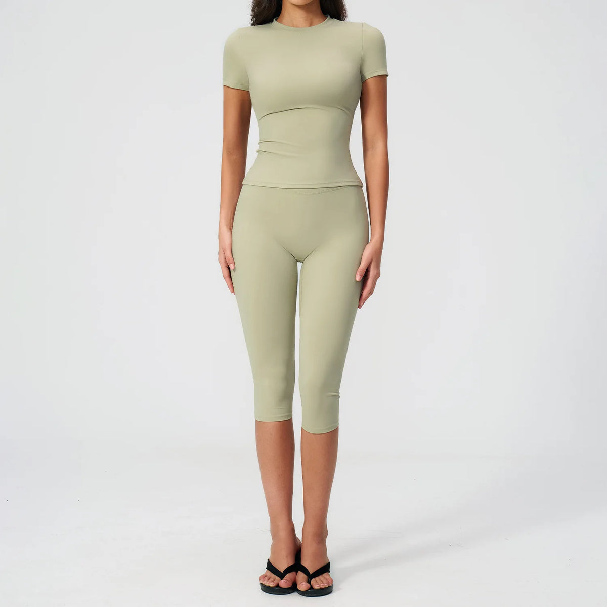A woman wearing a light olive green women's premium fitness tracksuit top and leggings.