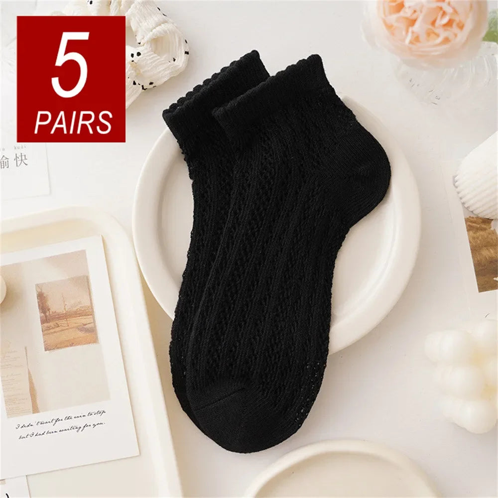 Five pairs of black breathable mesh lace tube socks displayed on a white plate.