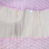 A light beige double compression waist trainer corset body shaper displayed on a pink quilted surface.