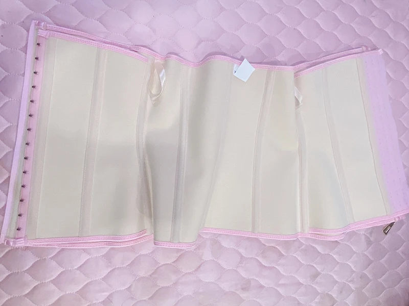 A light beige double compression waist trainer corset body shaper displayed on a pink quilted surface.