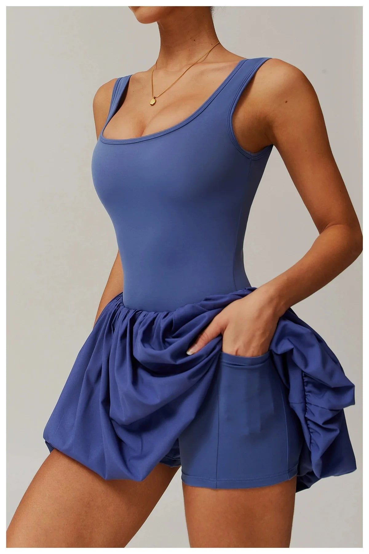 Model in a royal blue performance tennis dress for activewear.