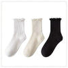 A set of three white and black cotton ruffle ankle socks displayed against a white background.