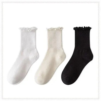 A set of three white and black cotton ruffle ankle socks displayed against a white background.