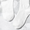 A pair of white crew socks with subtle lettering lying on a light textured surface.