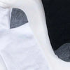A close-up view of white and black ankle socks with gray accents lying on a white surface.