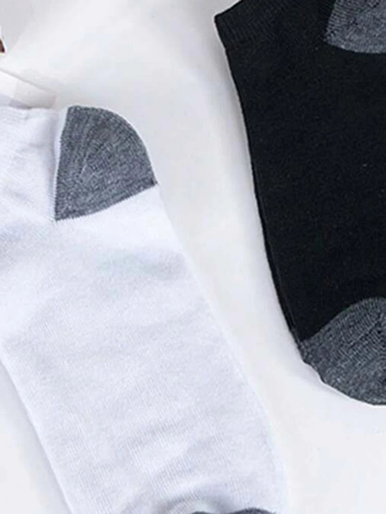 A close-up view of white and black ankle socks with gray accents lying on a white surface.