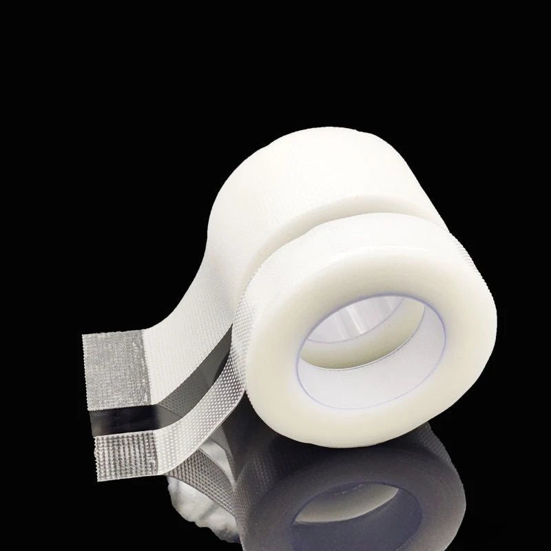 Roll of transparent fabric eyelash extension tape on a dark surface.
