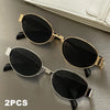 A pair of classic oval metal sunglasses in gold and silver tones resting on a gray surface.