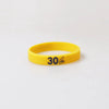 Yellow silicone wristband with the number 30 printed on it.