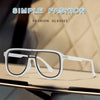 A pair of clear, square fashion glasses with white frames resting on a dark surface.