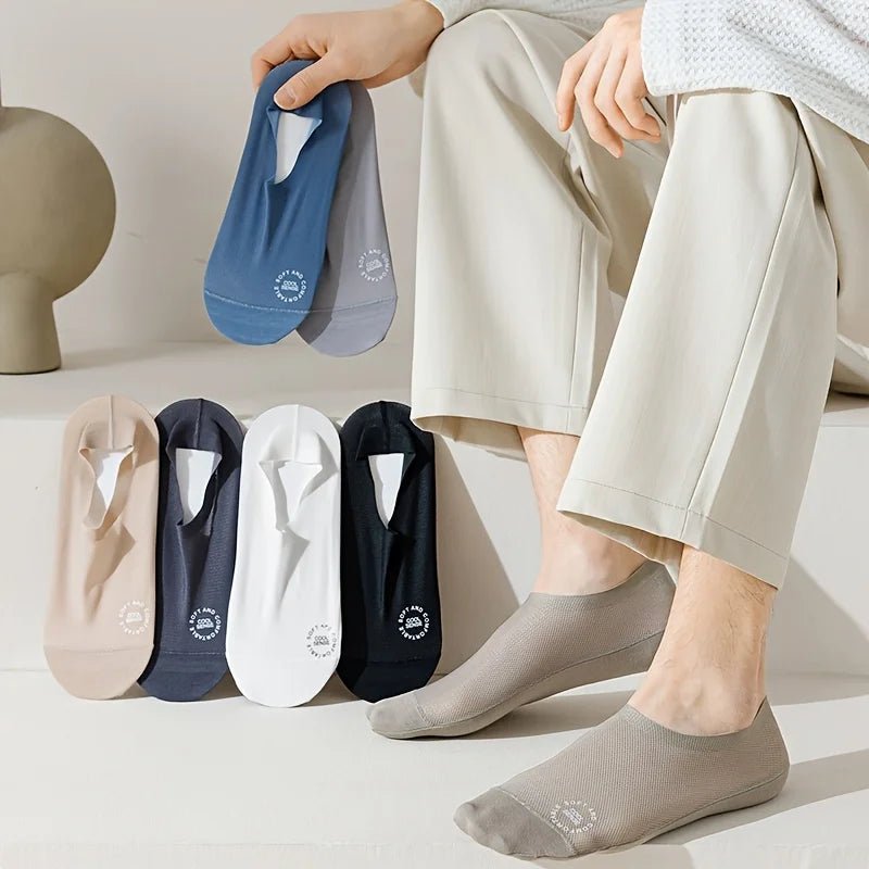 Una mano sostiene un paquete de calcetines de verano transpirables en varios tonos de azul y gris, junto a la pierna de una p