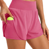 Ein Model trägt leuchtend pinke, hochgeschnittene Sportshorts mit Seitentasche und einem limettengrünen Ball.