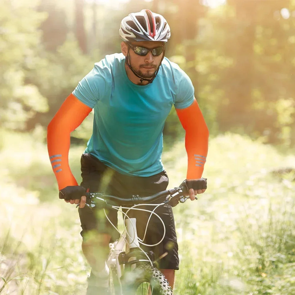 Ein Mann trägt ein türkises Sportshirt und orangefarbene Ärmel und fährt Fahrrad in einer sonnigen, grünen Umgebung.