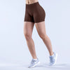 A person is wearing brown seamless high-waisted yoga shorts and light gray athletic shoes.