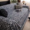 A plush sofa covered with a leopard print blanket featuring black and white spots.