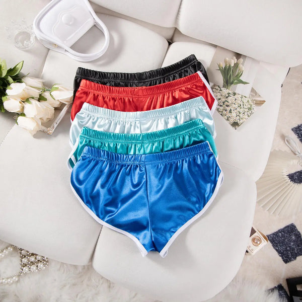 A stack of women's elastic waist running shorts in various colors like black, red, pink, and blue, resting on a white surface