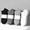 Un set de tres calcetines unisex de algodón transpirable en negro, gris y blanco.