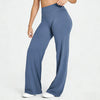 A woman wearing dark blue high waisted yoga pants standing against a light background.