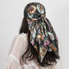 A woman wearing a patterned silk paisley shawl scarf with dark green and black floral designs.