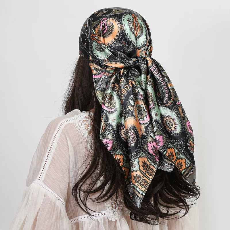 A woman wearing a patterned silk paisley shawl scarf with dark green and black floral designs.