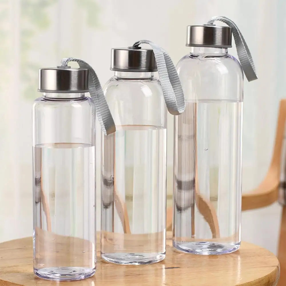 Trois bouteilles d'eau sport en plastique transparent avec des bouchons argentés et des bretelles grises sur une surface en b