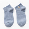 A pair of light gray cotton socks embroidered with a small owl