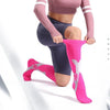 A person wearing pink compression socks on their feet while exercising or stretching.