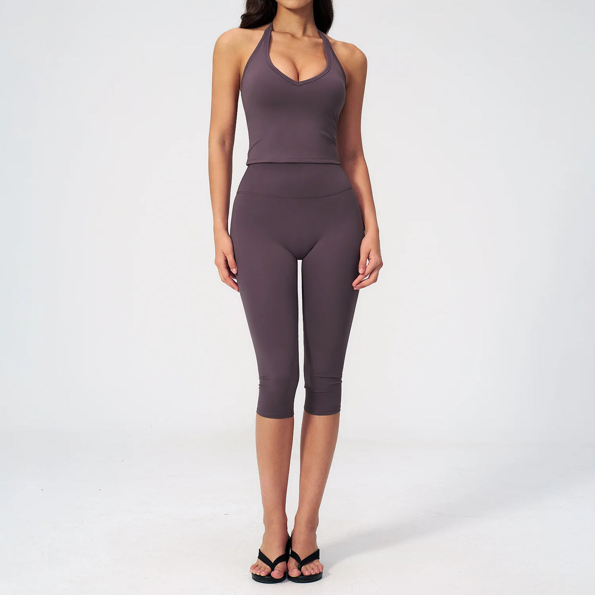 A woman wearing a dark purple women's premium fitness tracksuit top and leggings.