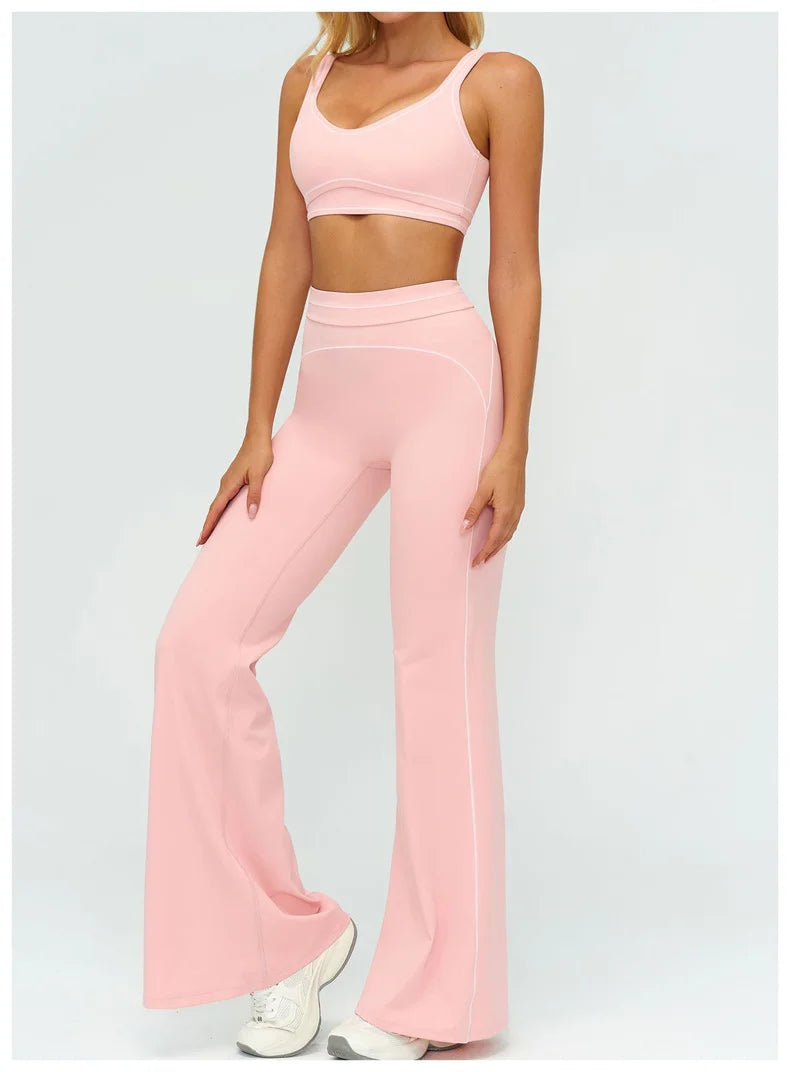 Una mujer modela un conjunto de ropa deportiva de yoga rosa claro de talle alto, compuesto por un top corto y pantalones a ju