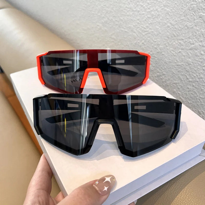 A pair of red and black cycling sunglasses resting on a white book.