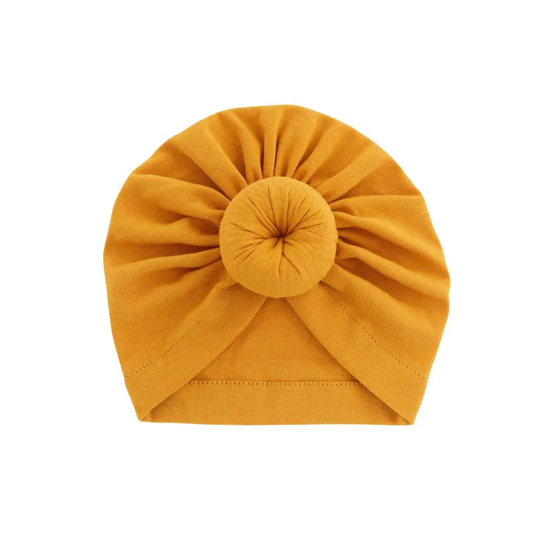 Ein aus solidem senfgelbem Baumwoll-Baby-Turban mit gebundener Knotenverzierung.