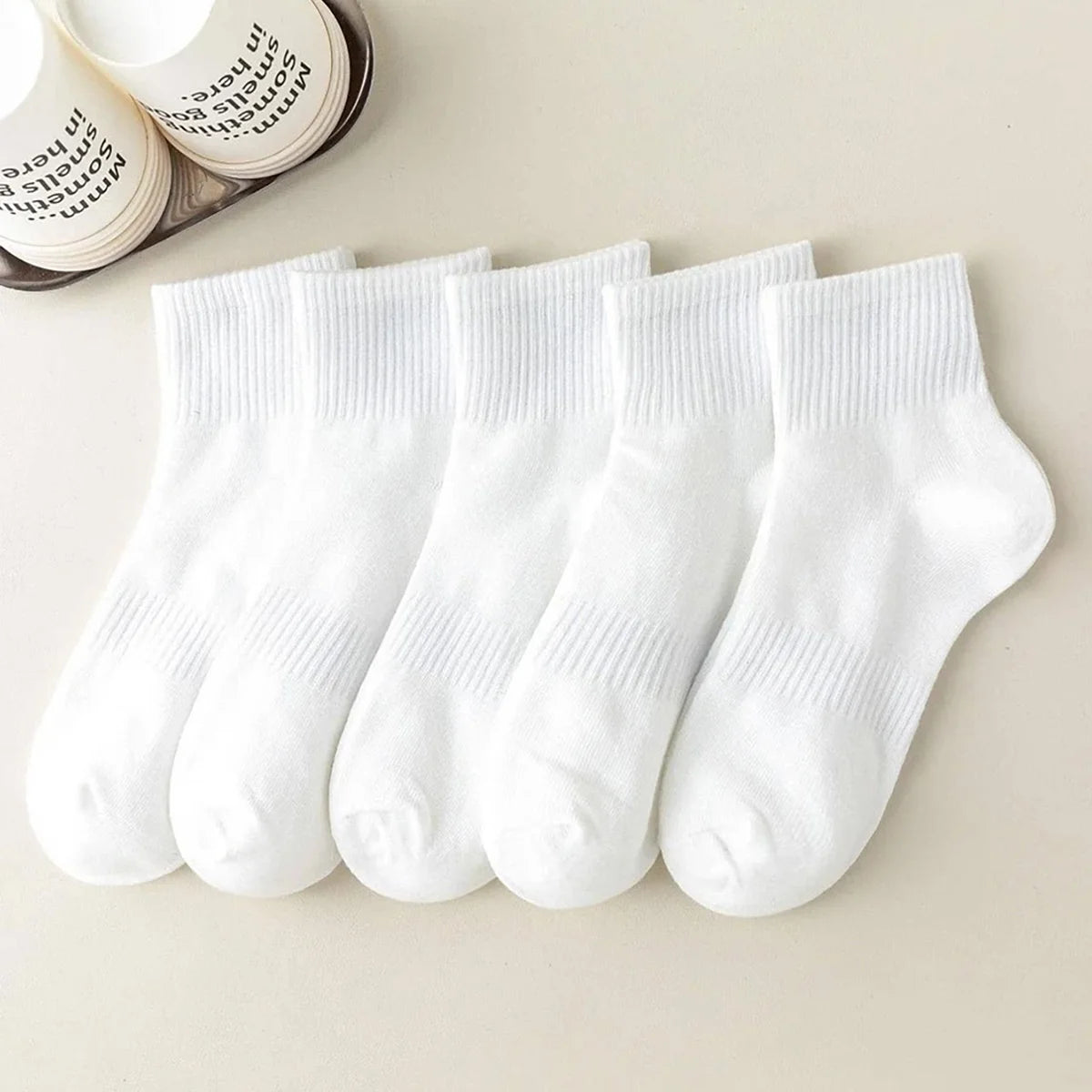 A row of white crew socks for men and women laid out on a light surface.