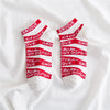 Pair of white socks with red lettering and stripes that read GOOVE and OOPS!