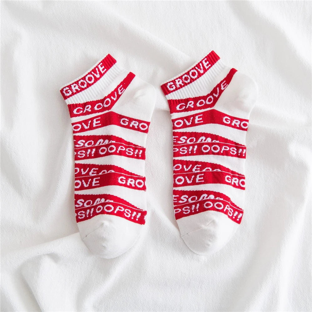 Pair of white socks with red lettering and stripes that read GOOVE and OOPS!