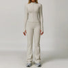 A woman wearing a beige long-sleeved top and matching pants from a 3-piece yoga sports set.